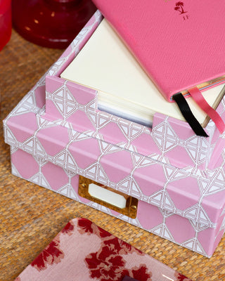 A pink portfolio box with a letter tray and a diary over a chest of drawers