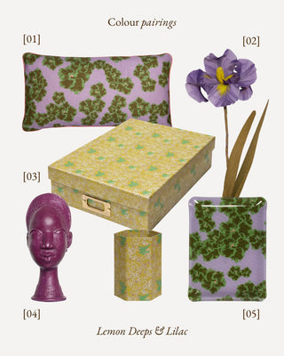 A coordinated home decor set on a light warm gray background, featuring a lavender pillow with a green floral pattern, a matching patterned box, a purple sculptural head vase, a matching patterned rectangular vase with dried stems, and text reading 'Colour pairings' and 'Lemon Deeps & Lilac'.