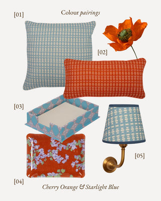 A styled color pairing collage on a light gray background showing coordinated home decor items in cherry orange and starlight blue: two patterned pillows, a decorative box, a wall lamp shade, and a flower prop. Text labels identify the color story and include [01], [02], [03], [04], and [05].